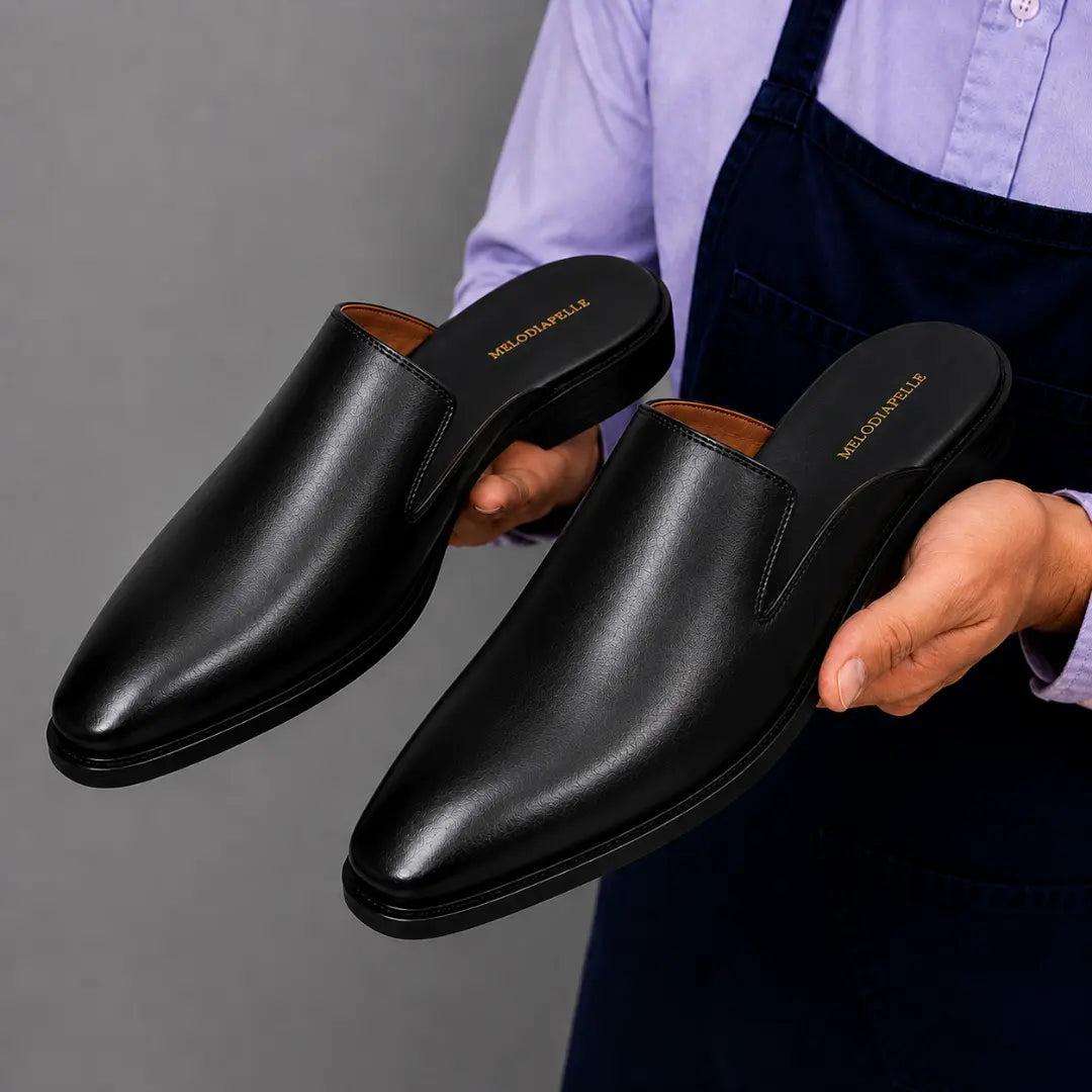 Man holding a pair of Melodiapelle Farida Mules in black leather, close-up