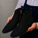 Man holding a pair of Melodiapelle Maddox Suede Zip Boots in black suede, close-up