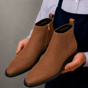 Man holding a pair of Melodiapelle Maddox Suede Zip Boots in tan suede, close-up
