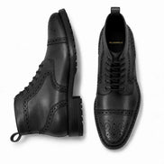 Black leather brogue combat boot, three-quarter angle showing heel and sole detailing