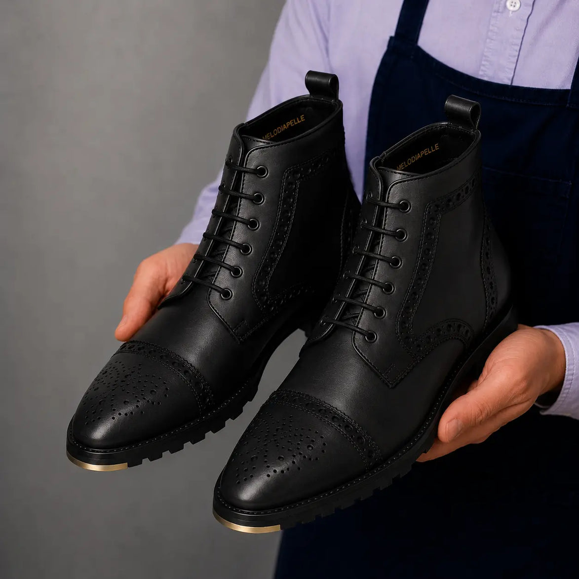 Man holding a pair of Melodiapelle Madison Combat Boots in black leather, close-up