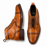 Tan leather brogue combat boot, three-quarter angle showing heel and sole detailing