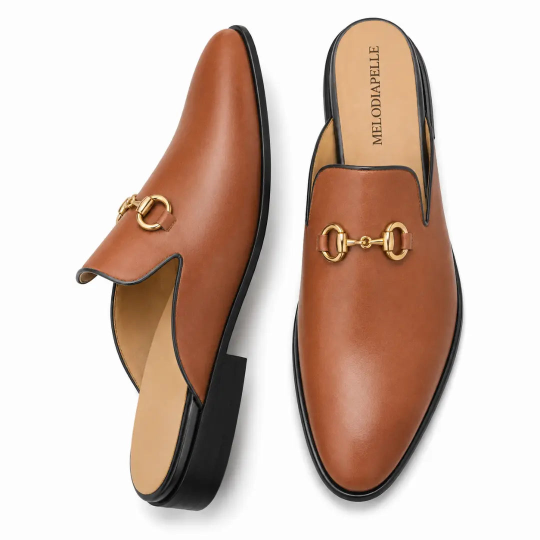 Tan leather horsebit mule, three-quarter angle showing buckle and heel