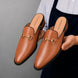 Man holding a pair of Melodiapelle Madison Mule shoes in tan leather, close-up