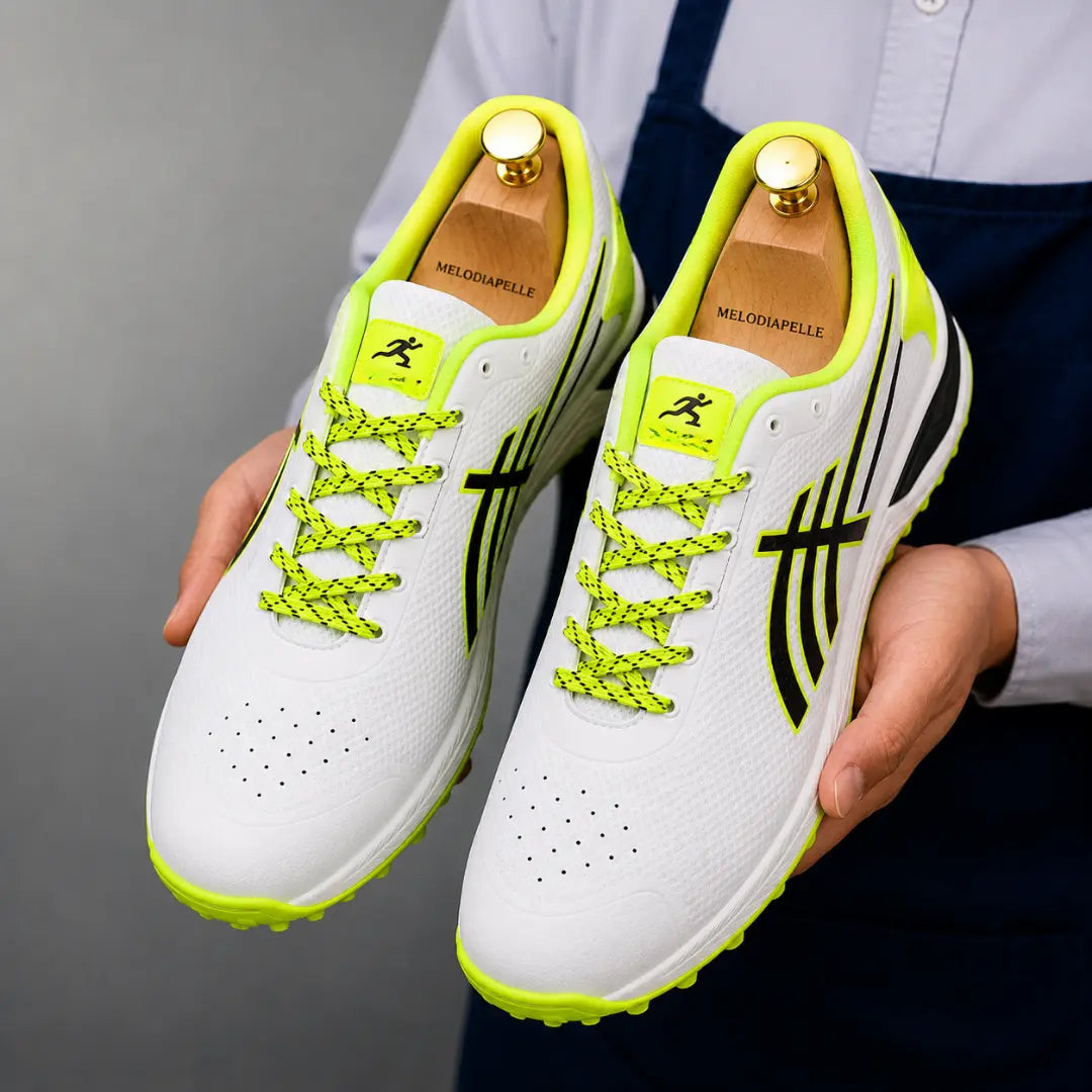 Man holding a pair of Melodiapelle Madras Cricket Shoes in white and neon yellow, close-up