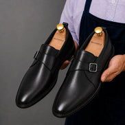Man holding a pair of Melodiapelle Madrid Single Monk Strap shoes in black leather, close-up