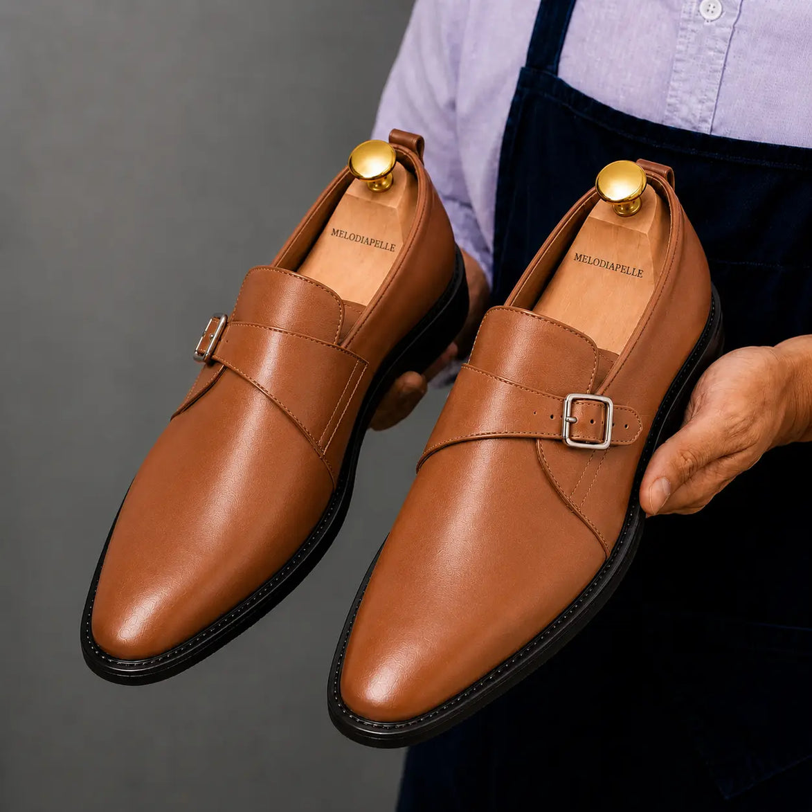 Man holding a pair of Melodiapelle Madrid Single Monk Strap shoes in tan leather, close-up