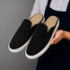 Man holding a pair of Melodiapelle Madurai Mule shoes in black suede, close-up