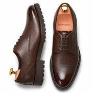 Dark brown leather plain-toe Derby, three-quarter angle showing heel and sole detailing