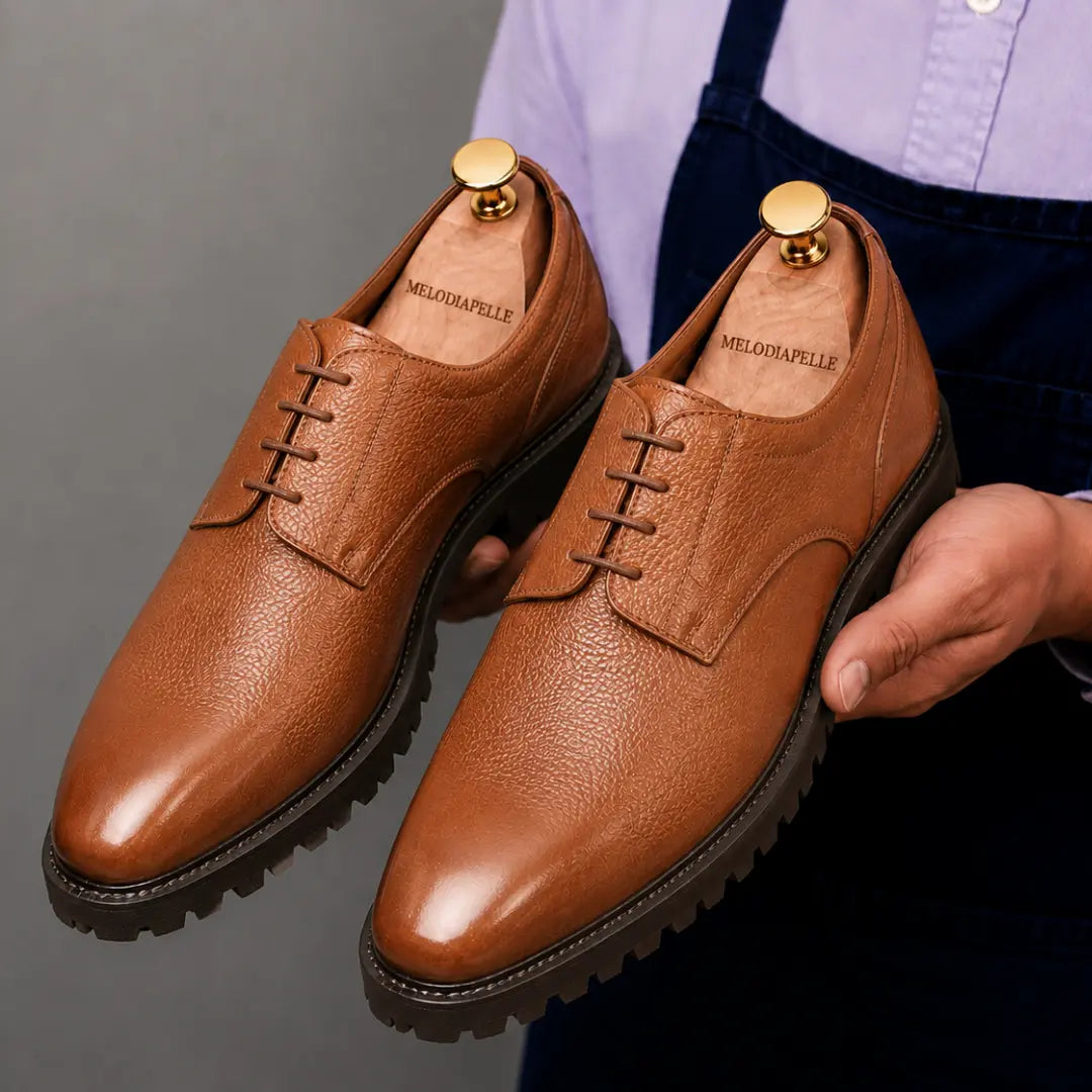 Man holding a pair of Melodiapelle Magnum Derby Shoes in tan leather, close-up