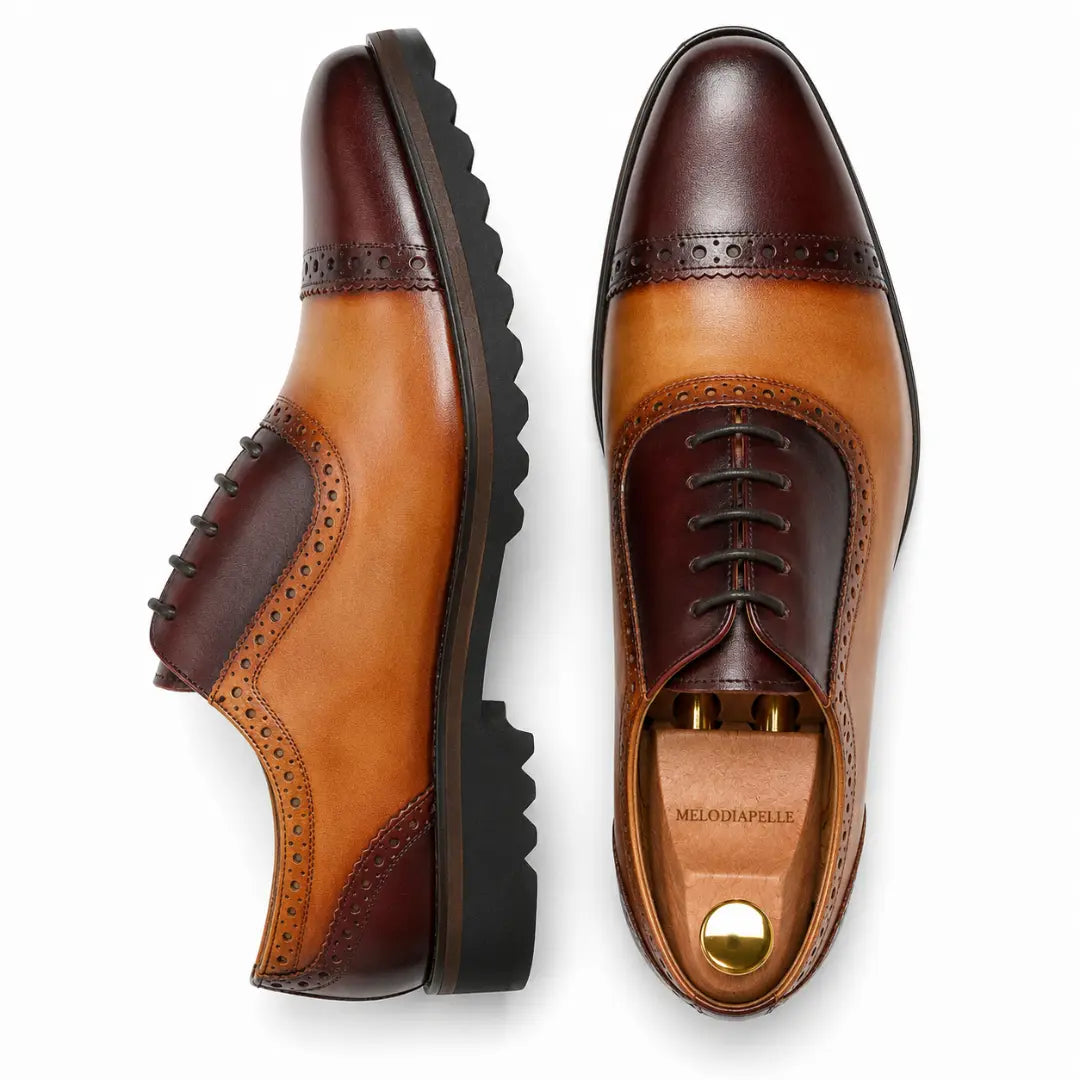 Two-tone tan and dark brown cap-toe Oxford, three-quarter angle showing heel and sole detailing