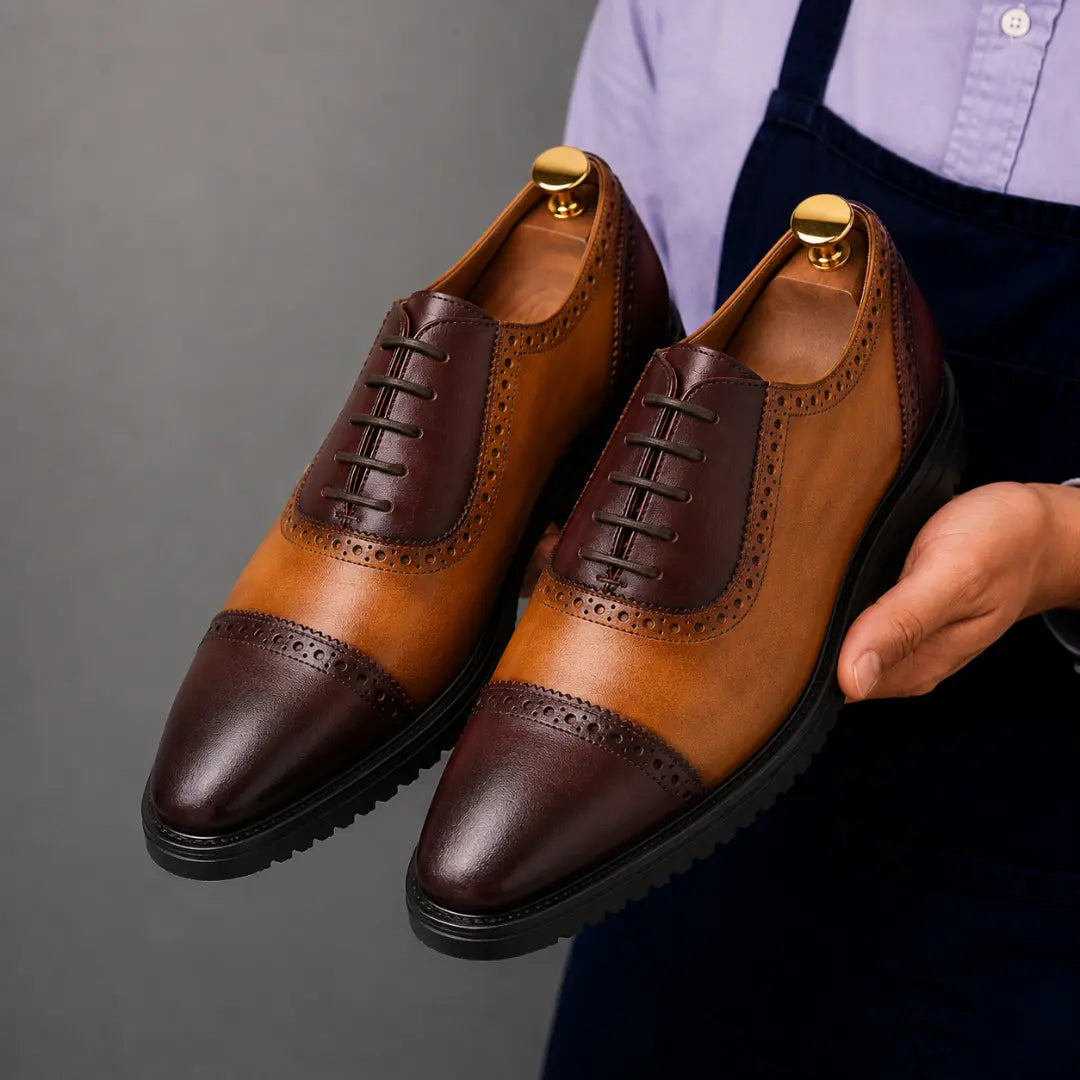Man holding a pair of Melodiapelle Maiden Oxford Shoes in tan and dark brown leather, close-up