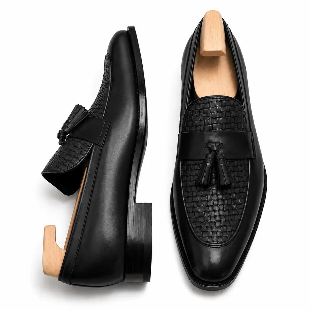Black woven leather penny loafer, three-quarter angle showing tassel and heel detailing