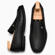 Black leather driving loafer, three-quarter angle showing moc-toe stitching and heel