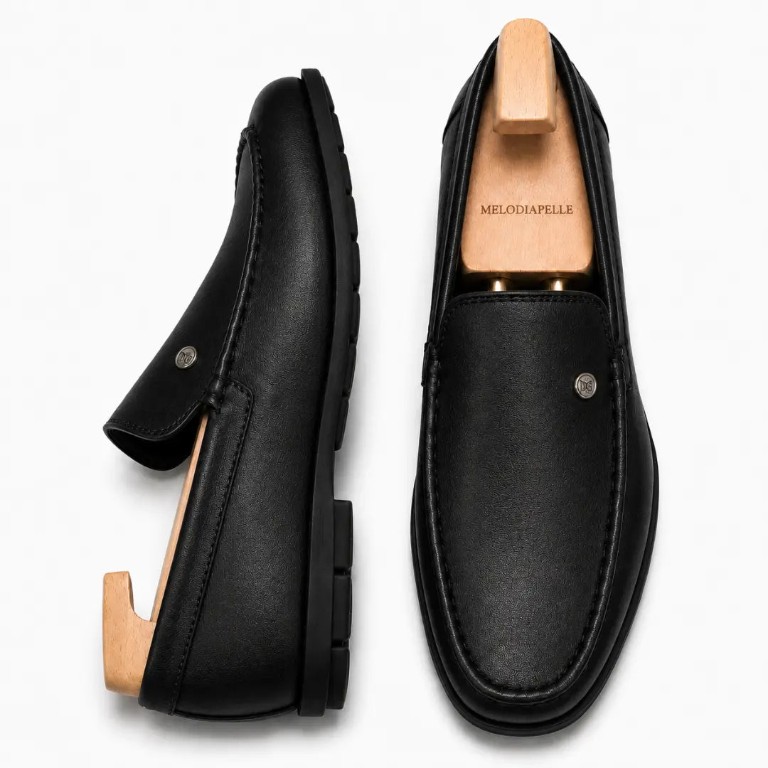 Black leather driving loafer, three-quarter angle showing moc-toe stitching and heel