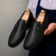 Man holding a pair of Melodiapelle Malaga Driving Loafer shoes in black leather, close-up