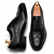 Black leather wingtip Derby, three-quarter angle showing croc-embossed panel and heel