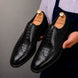 Man holding a pair of Melodiapelle Malcomb Croc-Panel Wingtip Derby shoes in black leather, close-up