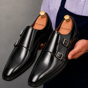 Man holding a pair of Melodiapelle Manchester Monk Strap shoes in black leather, close-up