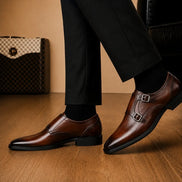 Man holding a pair of Melodiapelle Manchester Monk Strap shoes in burgundy leather, close-up