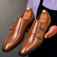 Man holding a pair of Melodiapelle Manchester Monk Strap shoes in tan leather, close-up