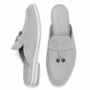 Light grey suede apron-toe tassel mule, three-quarter angle showing tassel and sole detailing