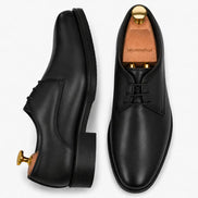 Black leather plain-toe Derby, three-quarter angle showing heel and clean upper