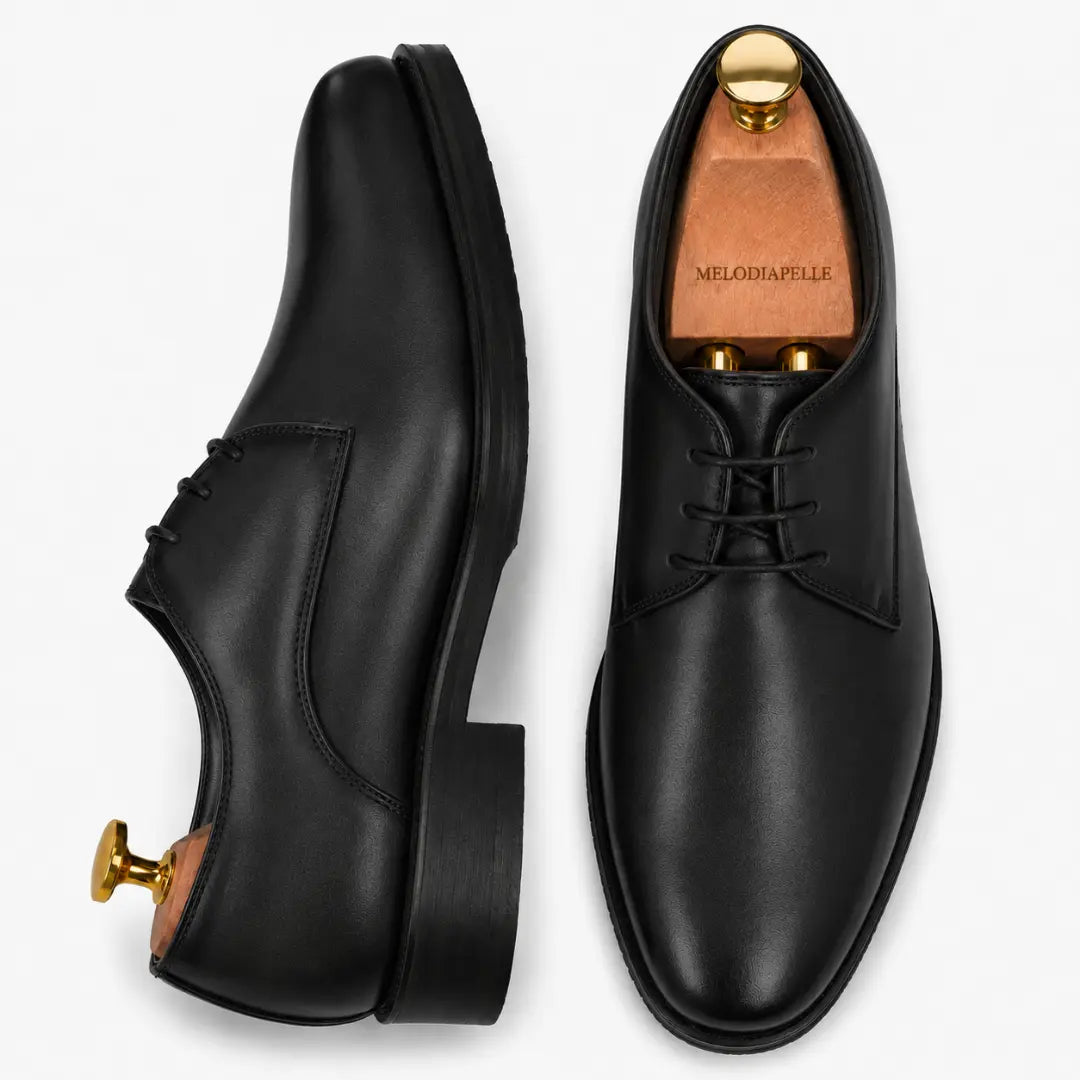 Black leather plain-toe Derby, three-quarter angle showing heel and clean upper