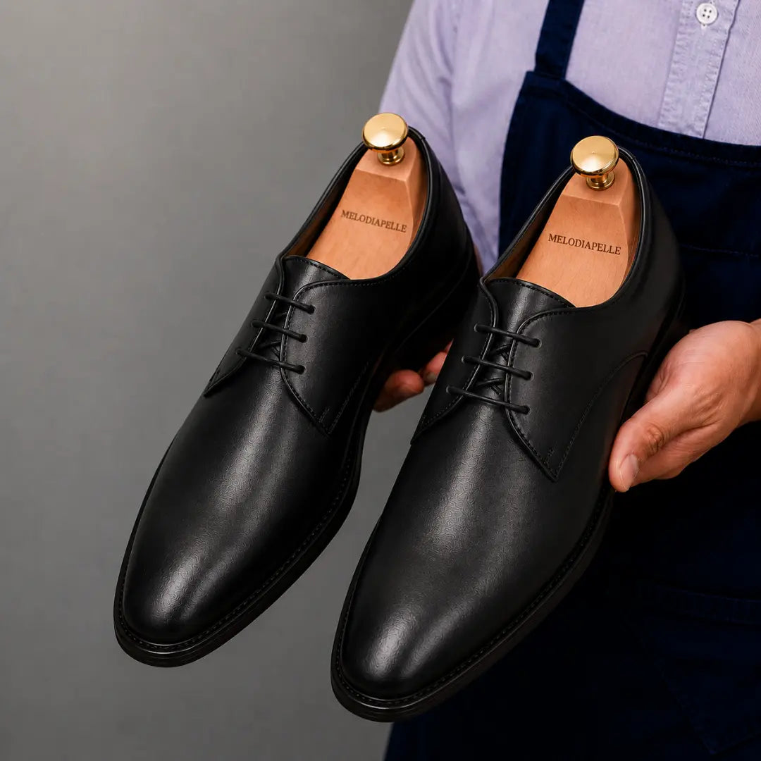 Man holding a pair of Melodiapelle Mangrove Plain Derby shoes in black leather, close-up