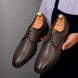Man holding a pair of Melodiapelle Mangrove Plain Derby shoes in brown leather, close-up