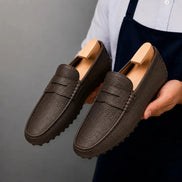 Man holding a pair of Melodiapelle Manhattan Loafers in dark brown leather, close-up