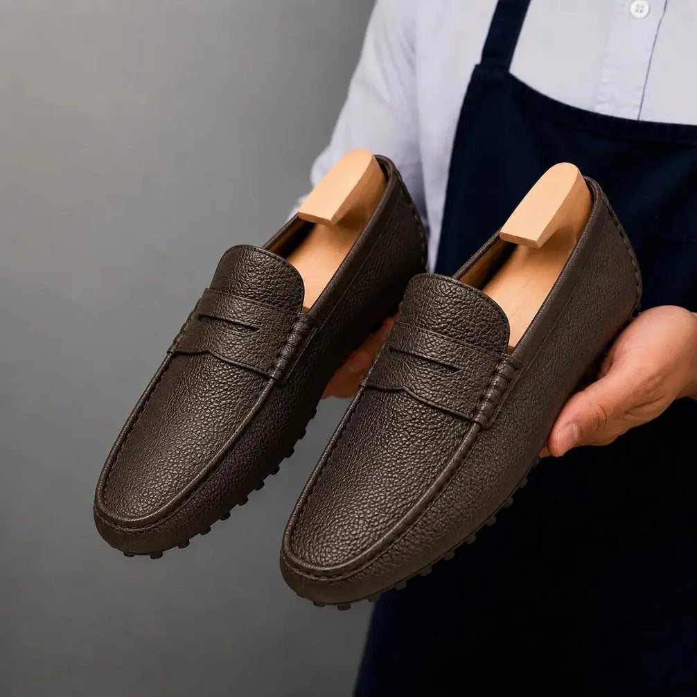 Man holding a pair of Melodiapelle Manhattan Loafers in dark brown leather, close-up