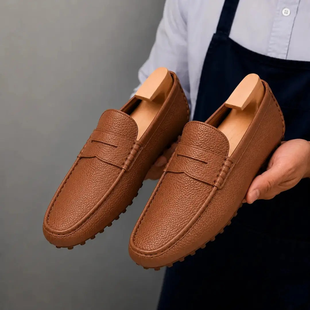 Man holding a pair of Melodiapelle Manhattan Loafers in rust tan leather, close-up