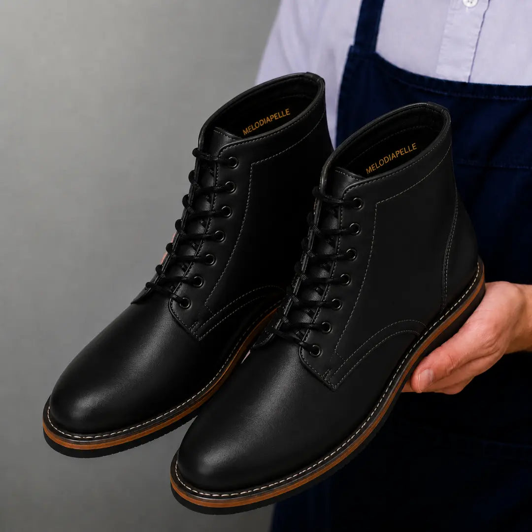Man holding a pair of Melodiapelle Manila Plain Toe Boots in black leather, close-up