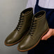 Man holding a pair of Melodiapelle Manila Plain Toe Boots in olive green leather, close-up