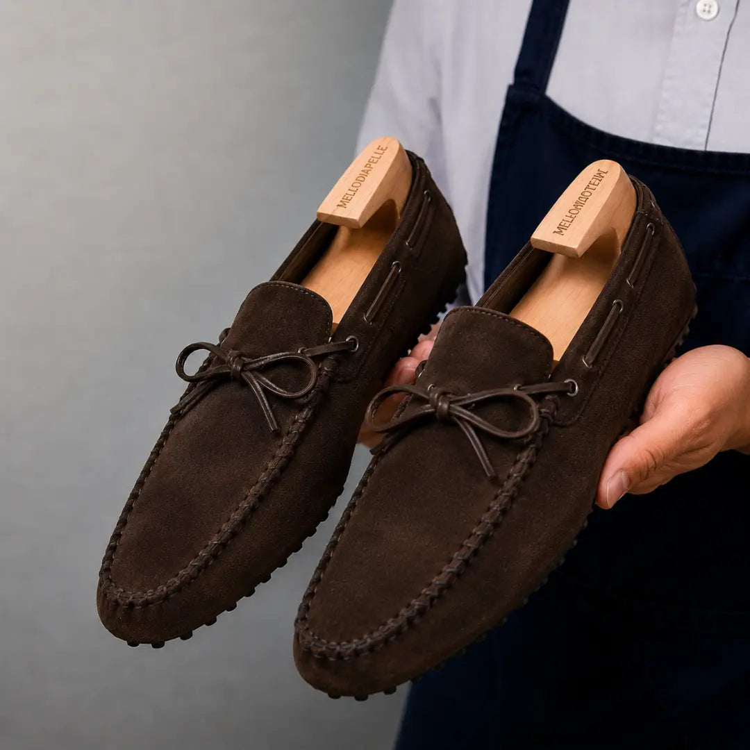 Man holding a pair of Melodiapelle Mansfield Loafers in dark brown suede, close-up