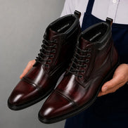 Man holding a pair of Melodiapelle Manteca Combat Boots in burgundy leather, close-up