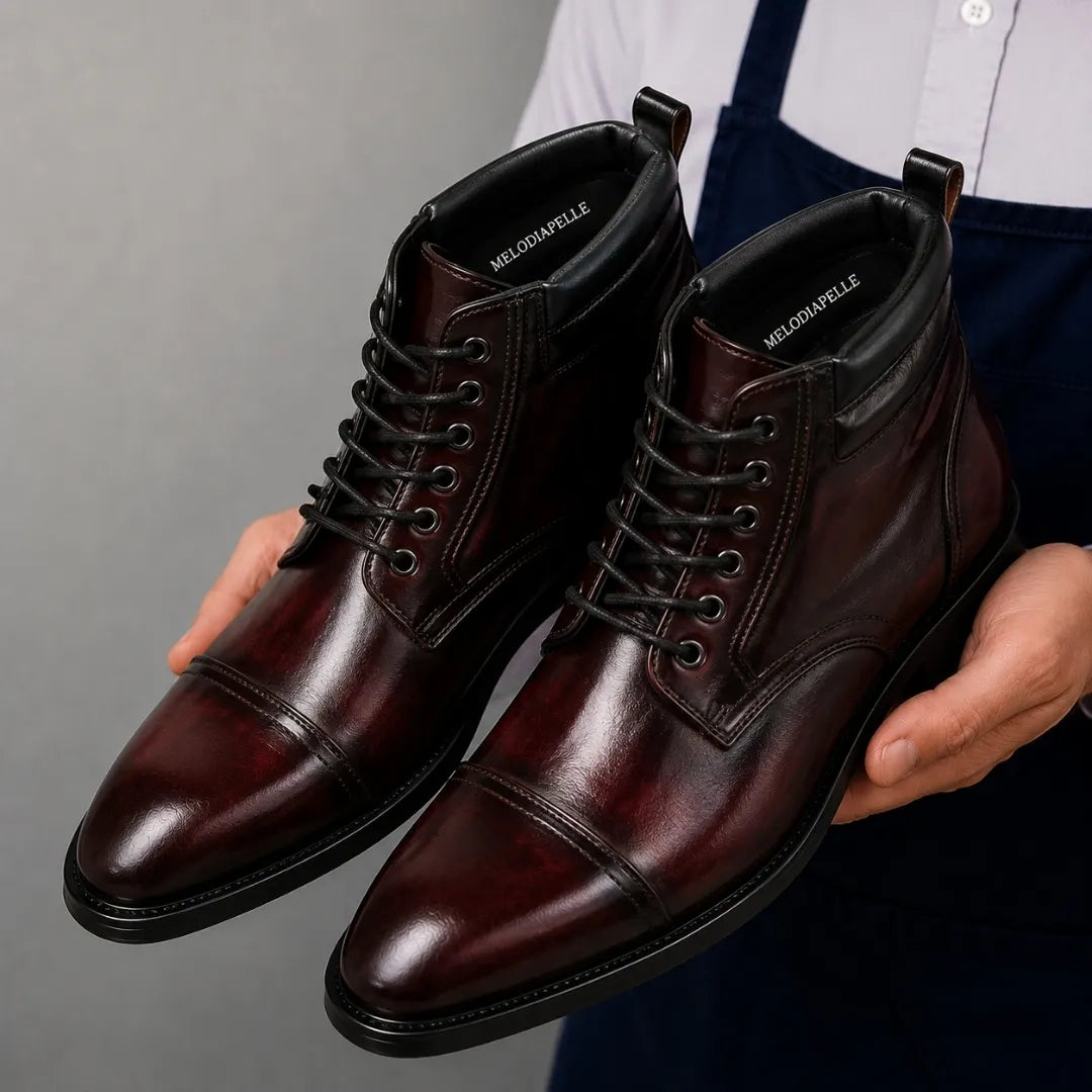 Man holding a pair of Melodiapelle Manteca Combat Boots in burgundy leather, close-up