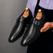 Man holding a pair of Melodiapelle Mapple Monkstrap shoes in black leather, close-up