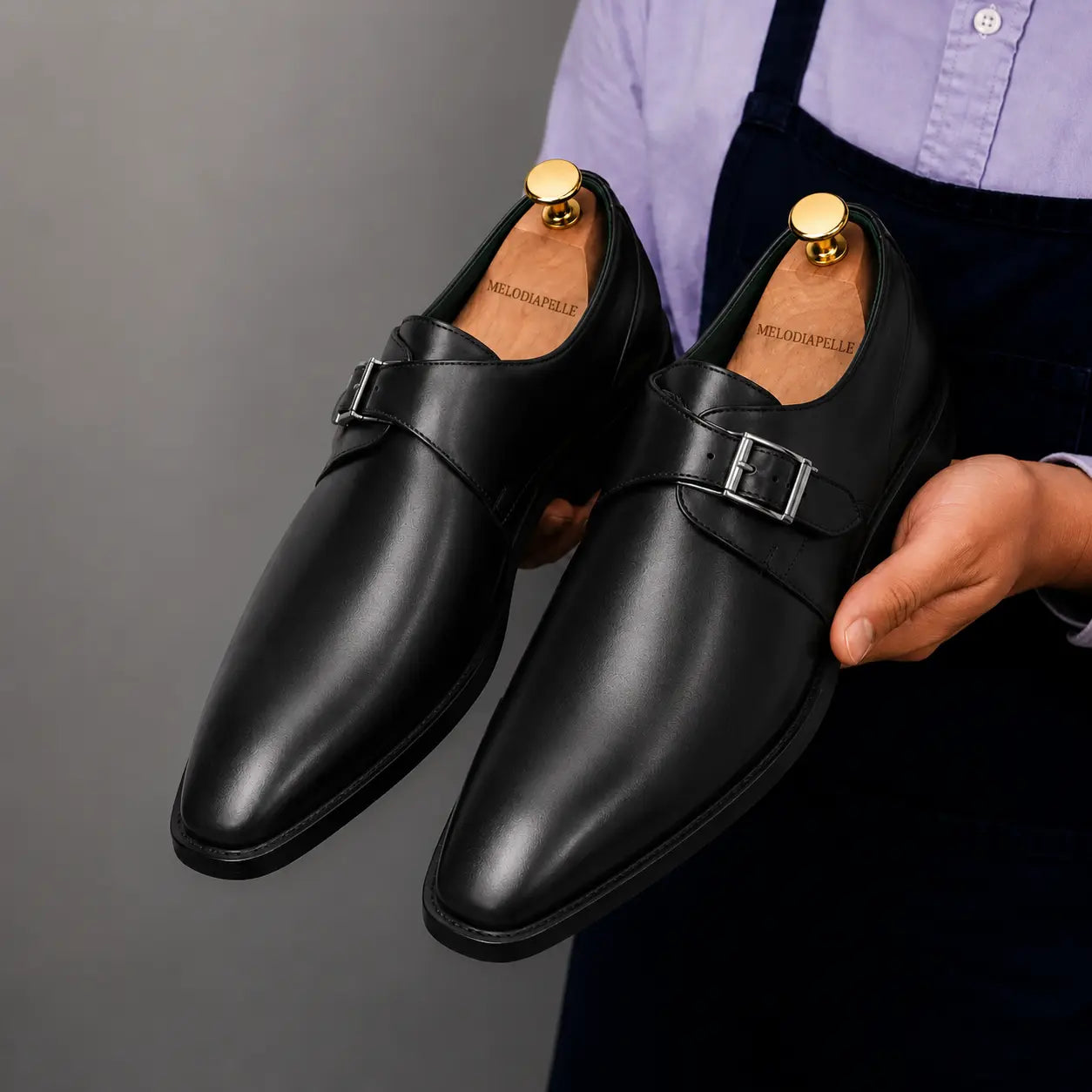 Man holding a pair of Melodiapelle Mapple Monkstrap shoes in black leather, close-up