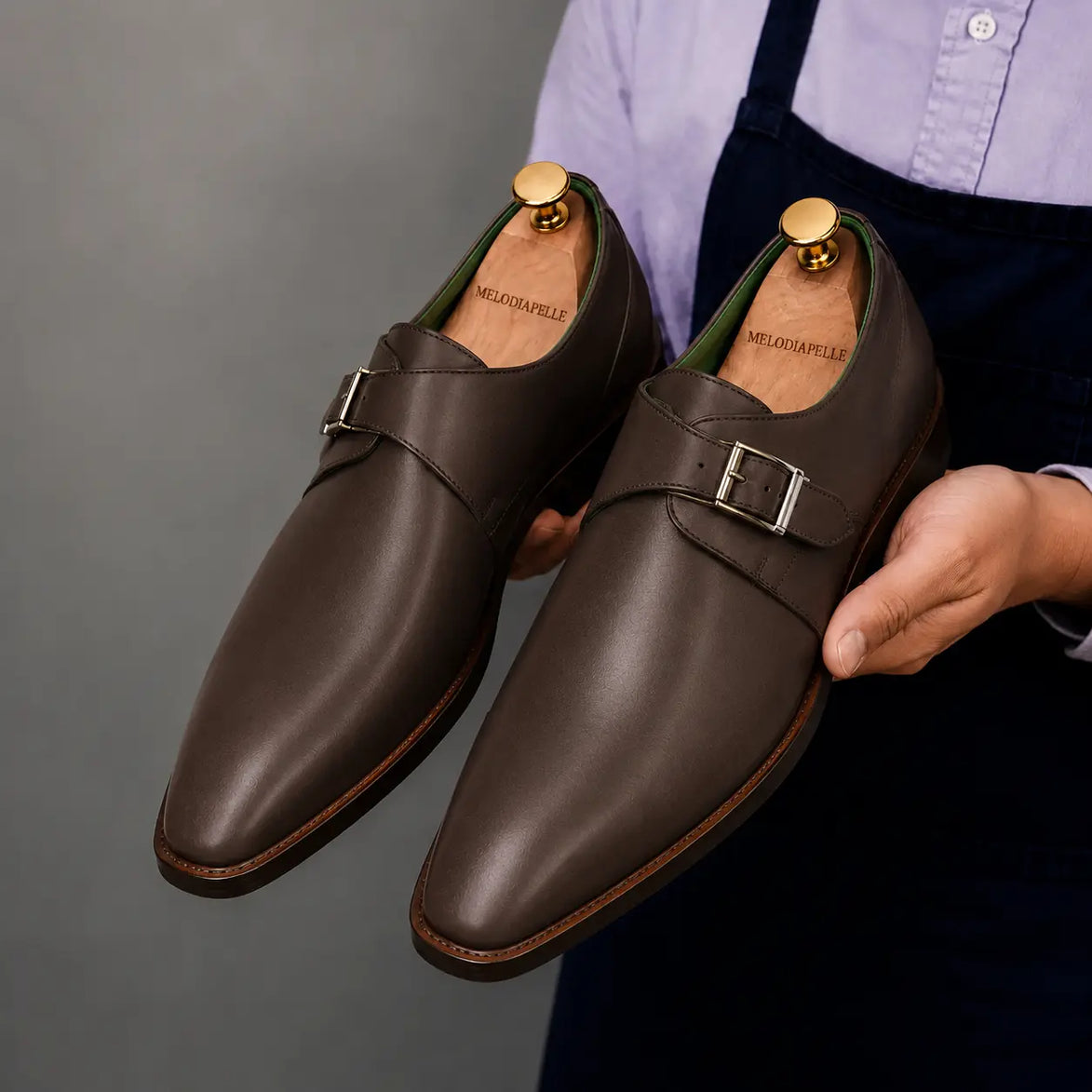 Man holding a pair of Melodiapelle Mapple Monkstrap shoes in dark brown leather, close-up