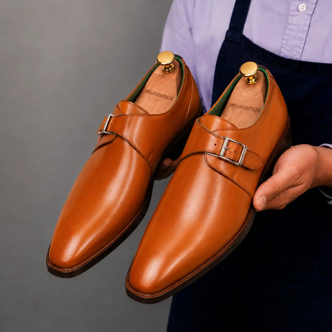 Man holding a pair of Melodiapelle Mapple Monkstrap shoes in tan leather, close-up