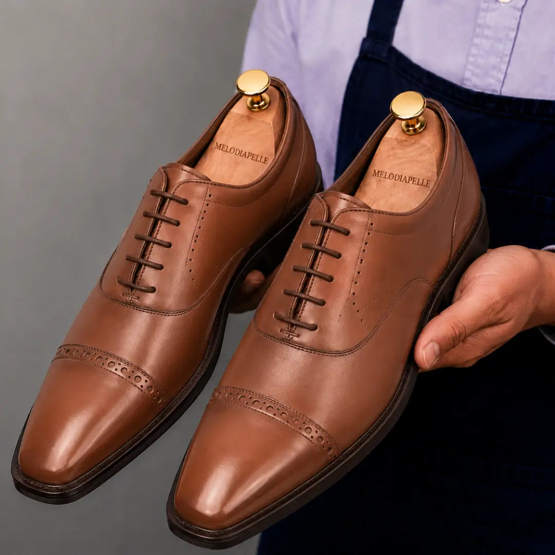 Man holding a pair of Melodiapelle Marcello Semi-Brogue Oxford shoes in tan leather, close-up