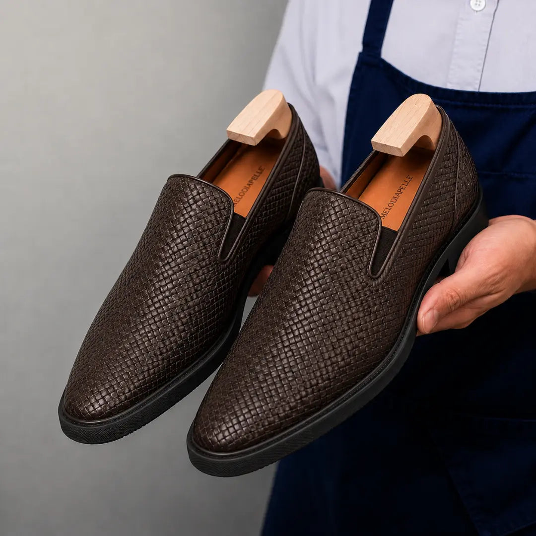 Man holding a pair of Melodiapelle Marengo Embossed Slip-On Sneakers in brown leather, close-up