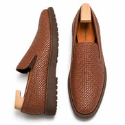 Tan embossed leather slip-on sneaker, three-quarter angle showing heel and woven texture