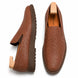 Tan embossed leather slip-on sneaker, three-quarter angle showing heel and woven texture