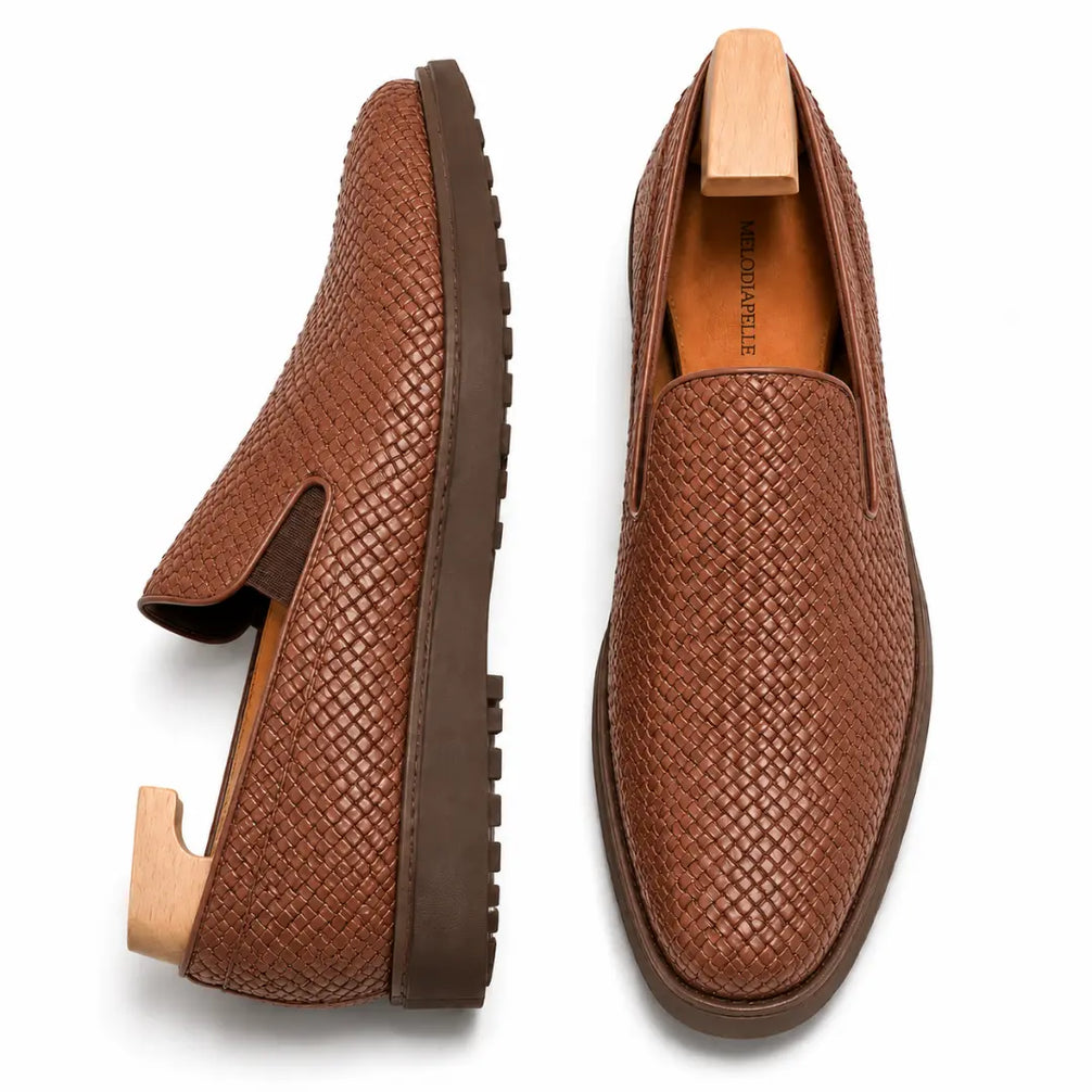 Tan embossed leather slip-on sneaker, three-quarter angle showing heel and woven texture