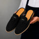 Man holding a pair of Melodiapelle Maria Mule shoes in black suede, close-up