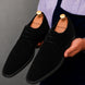 Man holding a pair of Melodiapelle Maringa Suede Chukka Boots in black suede, close-up