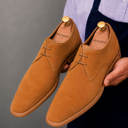 Man holding a pair of Melodiapelle Maringa Suede Chukka Boots in camel suede, close-up